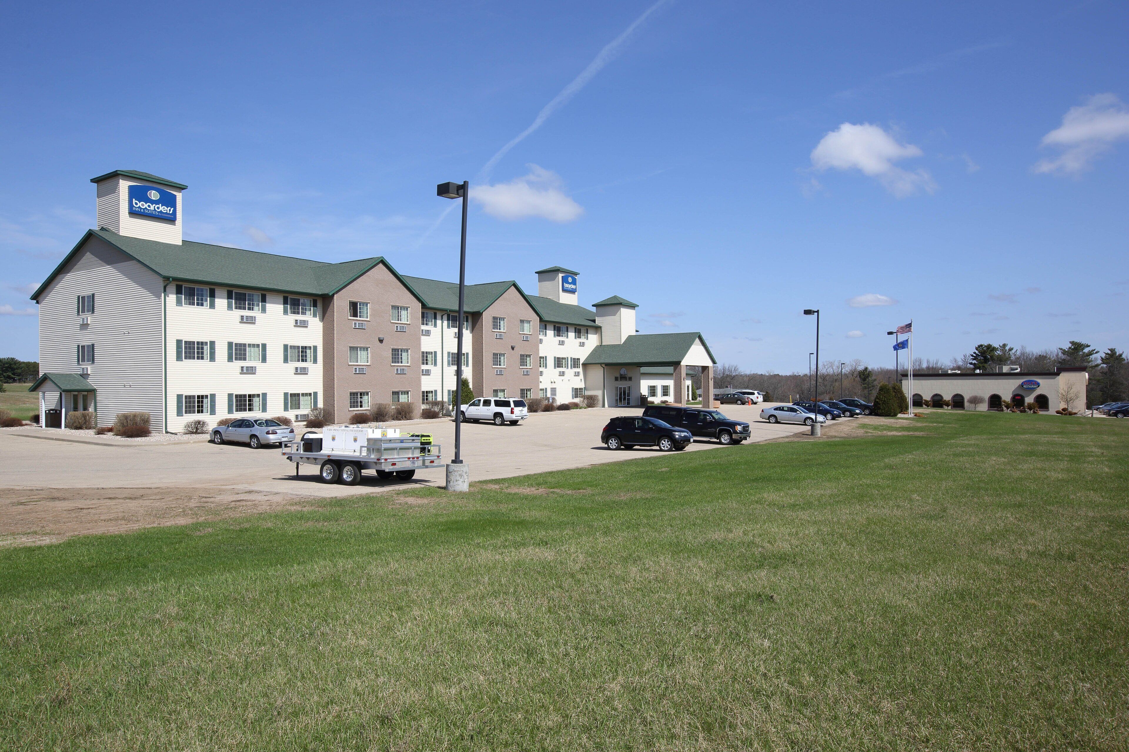 A hotel with multiple buildings, a parking lot, and a grassy area.