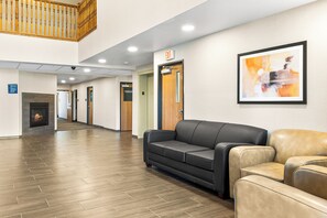 A lobby with a fireplace, a black and beige sofa, and a framed abstract painting on the wall. - Boarders Inn & Suites by Cobblestone Hotels - Shawano (Shawano)