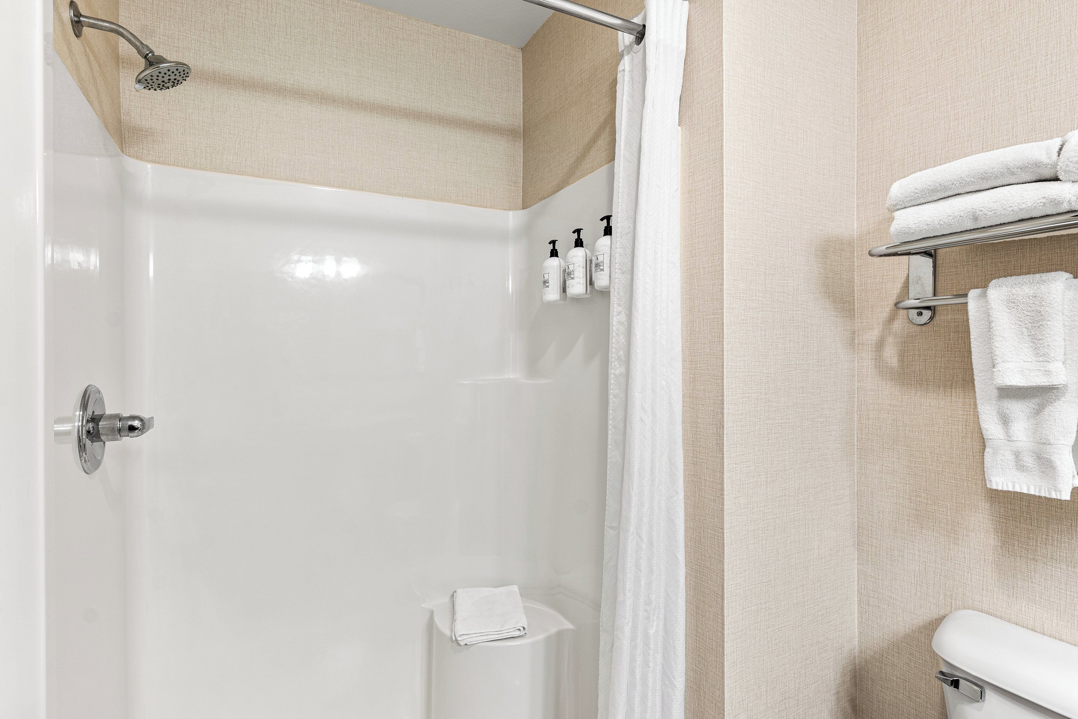 A modern bathroom with a glass-enclosed shower, a toilet, and a towel rack.