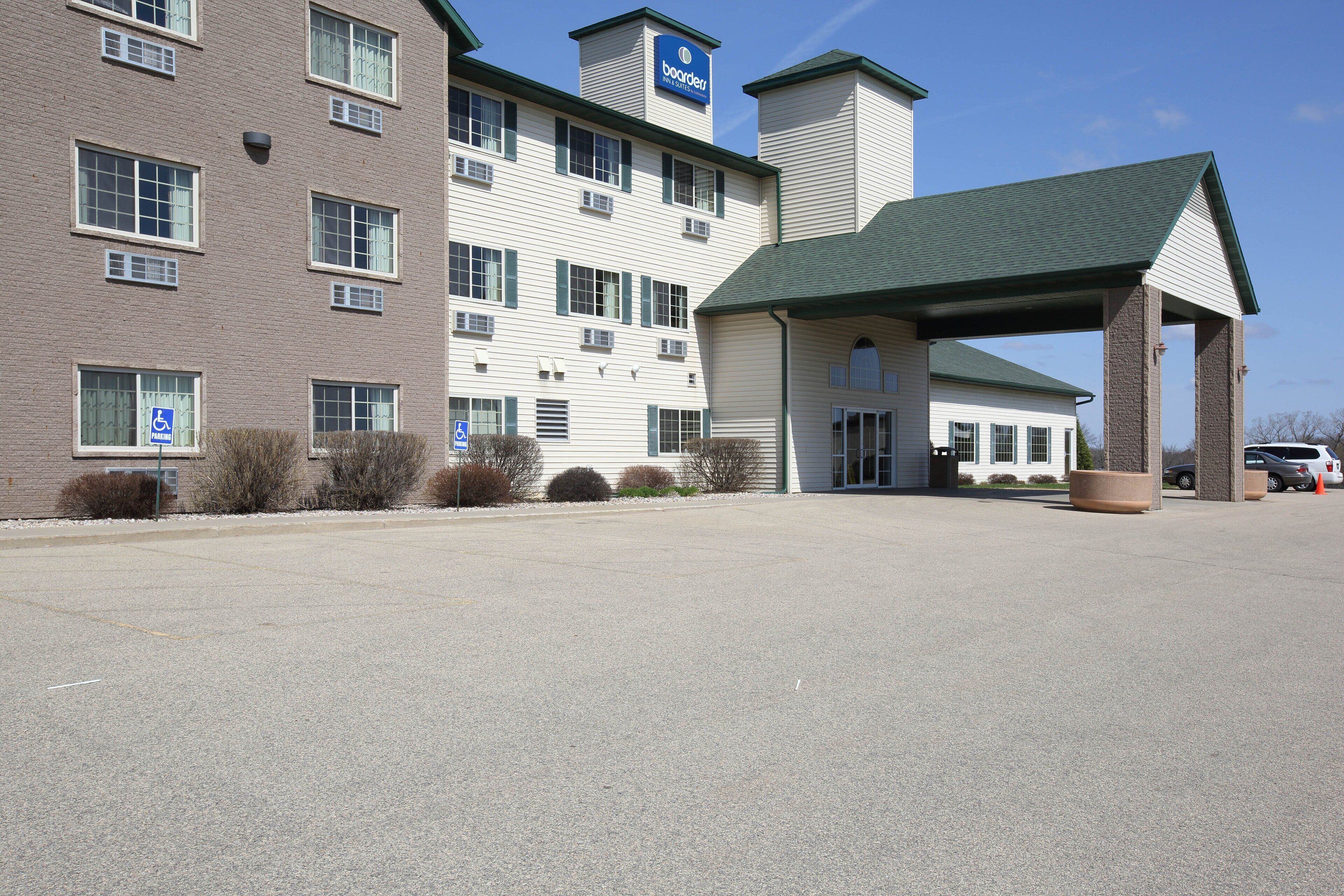 A hotel with a covered entrance, a parking lot, and a handicap-accessible sign.