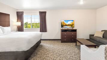 Une chambre d’hôtel avec un lit, une télévision, un canapé et une fenêtre avec des rideaux.