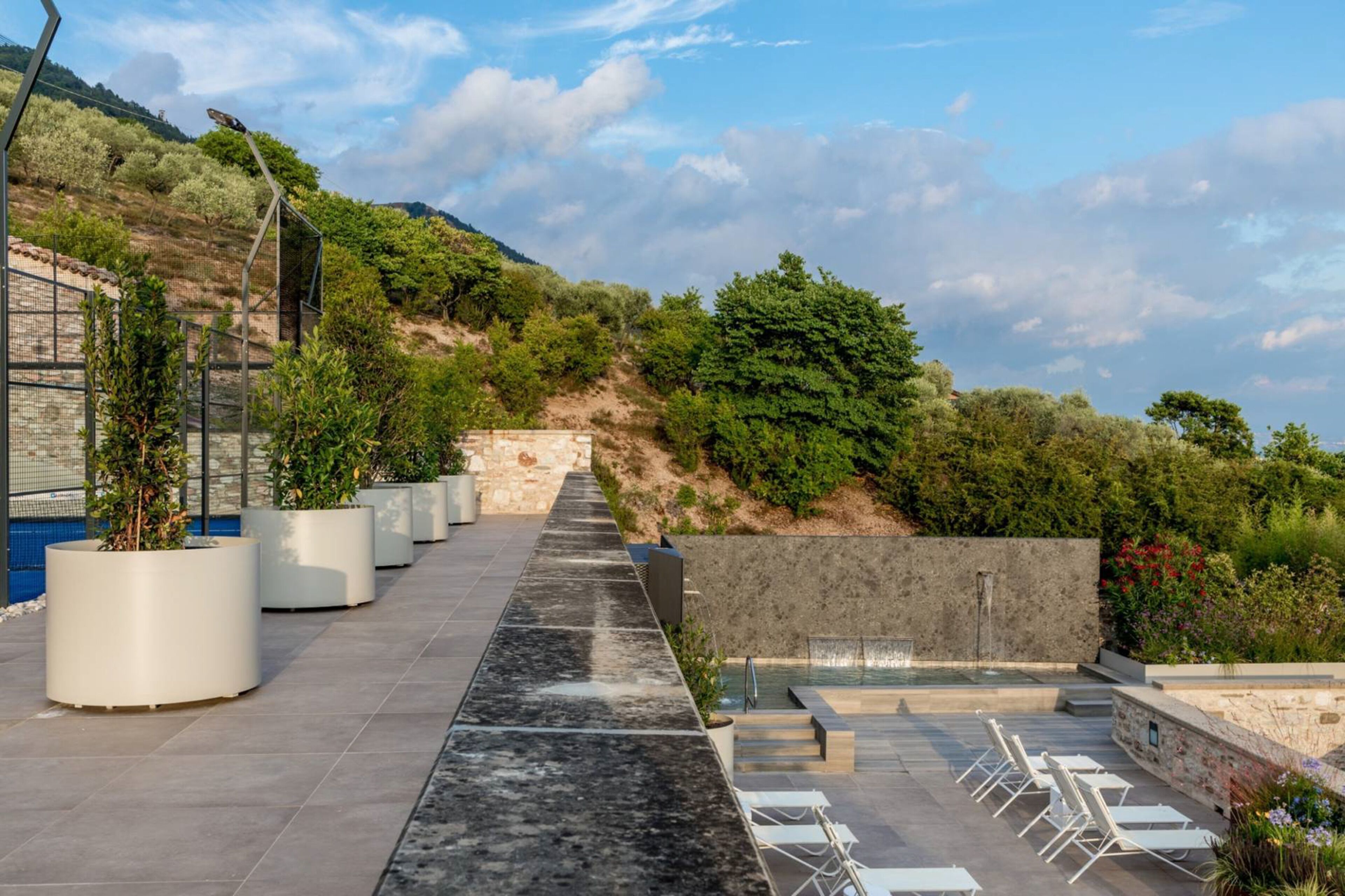 A rooftop terrace with a pool, seating area, and potted plants.