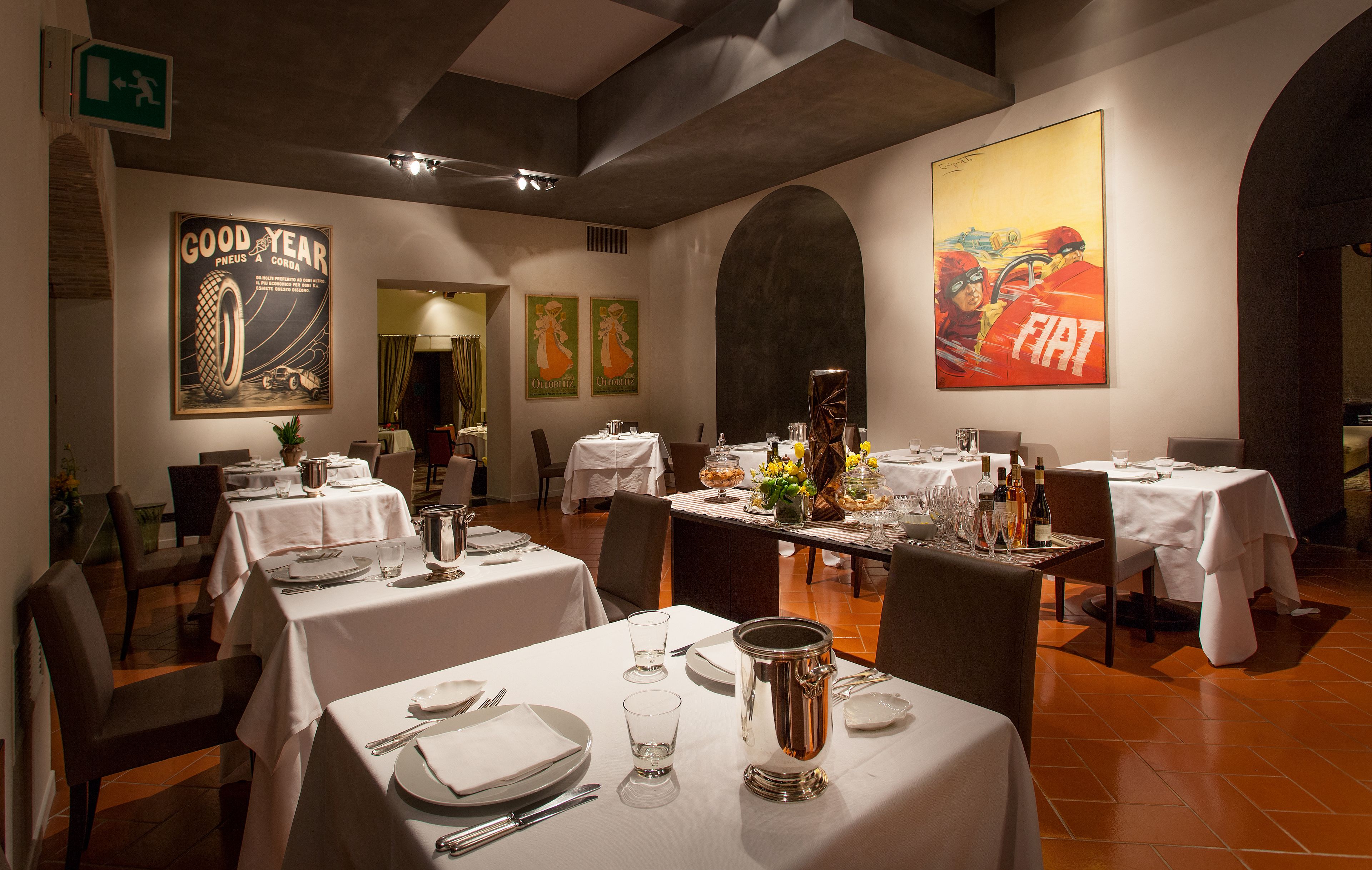A restaurant with tables set for dining, featuring classic decor and vintage posters on the walls.