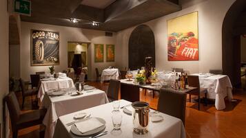 A restaurant with tables set for dining, featuring classic decor and vintage posters on the walls.