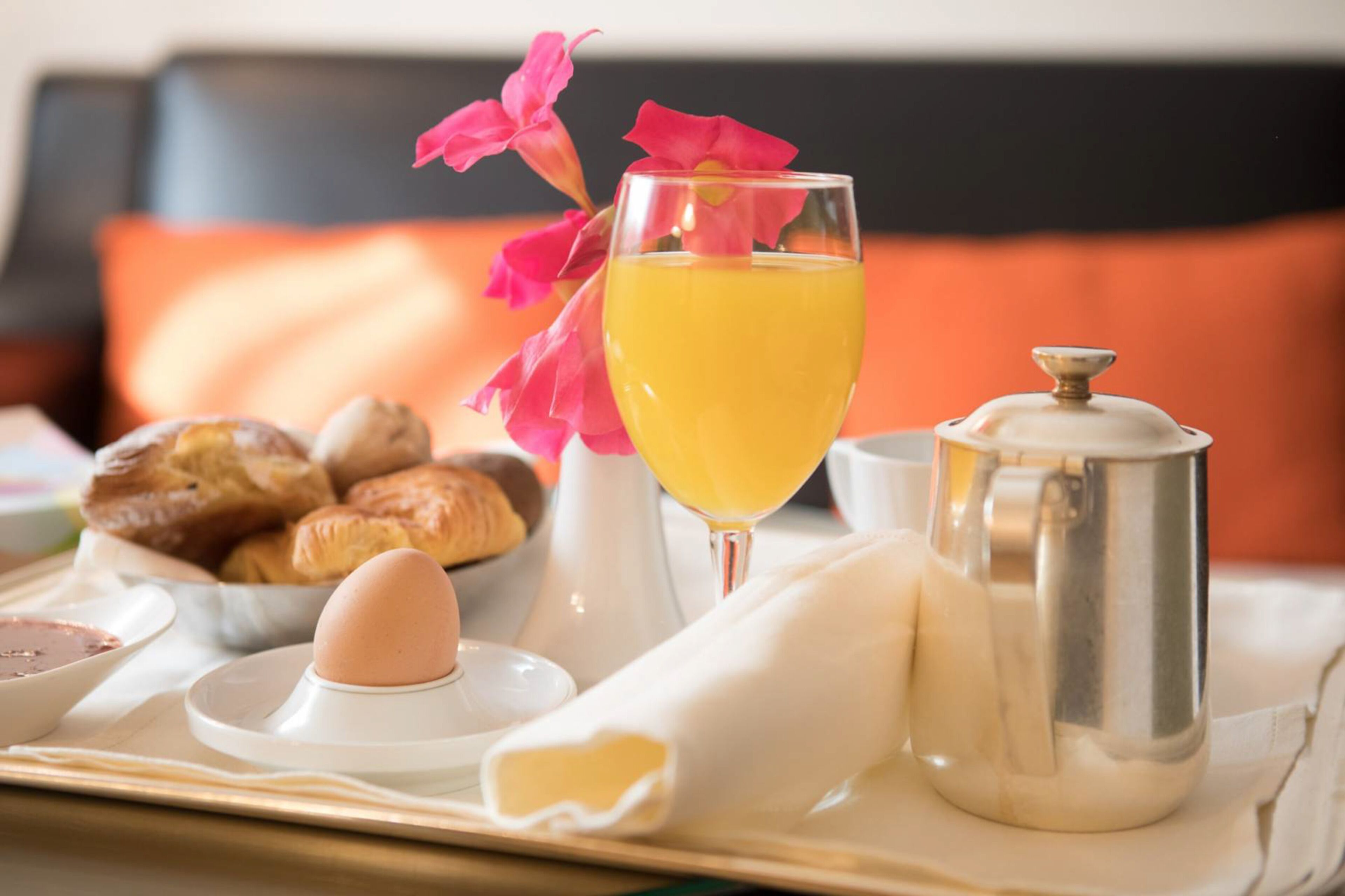 Bandeja de desayuno con croissants, un vaso de zumo de naranja, una cafetera y un cuenco de mantequilla.