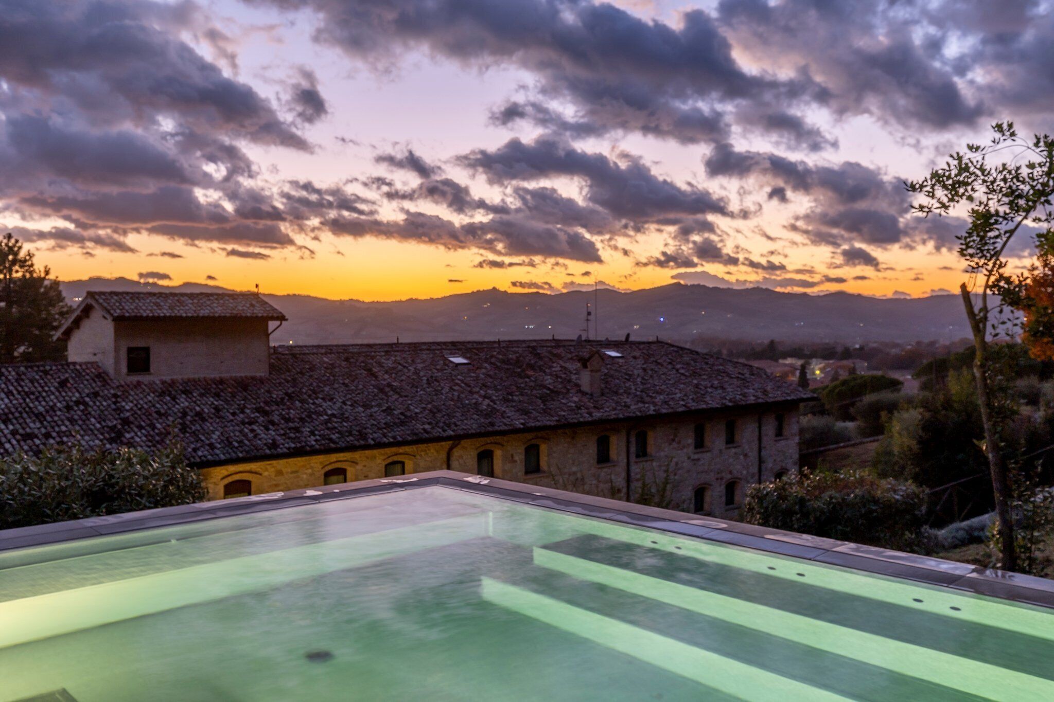 Una piscina en la azotea con vistas a un edificio histórico y montañas al fondo.