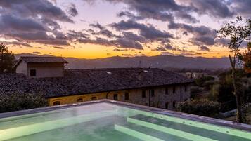 Una piscina en la azotea con vistas a un edificio histórico y montañas al fondo.