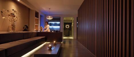 A modern interior with a long reception desk, a seating area, and a hallway leading to a door.