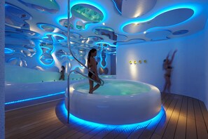 Piscina interior moderna con diseño de techo único e iluminación azul.