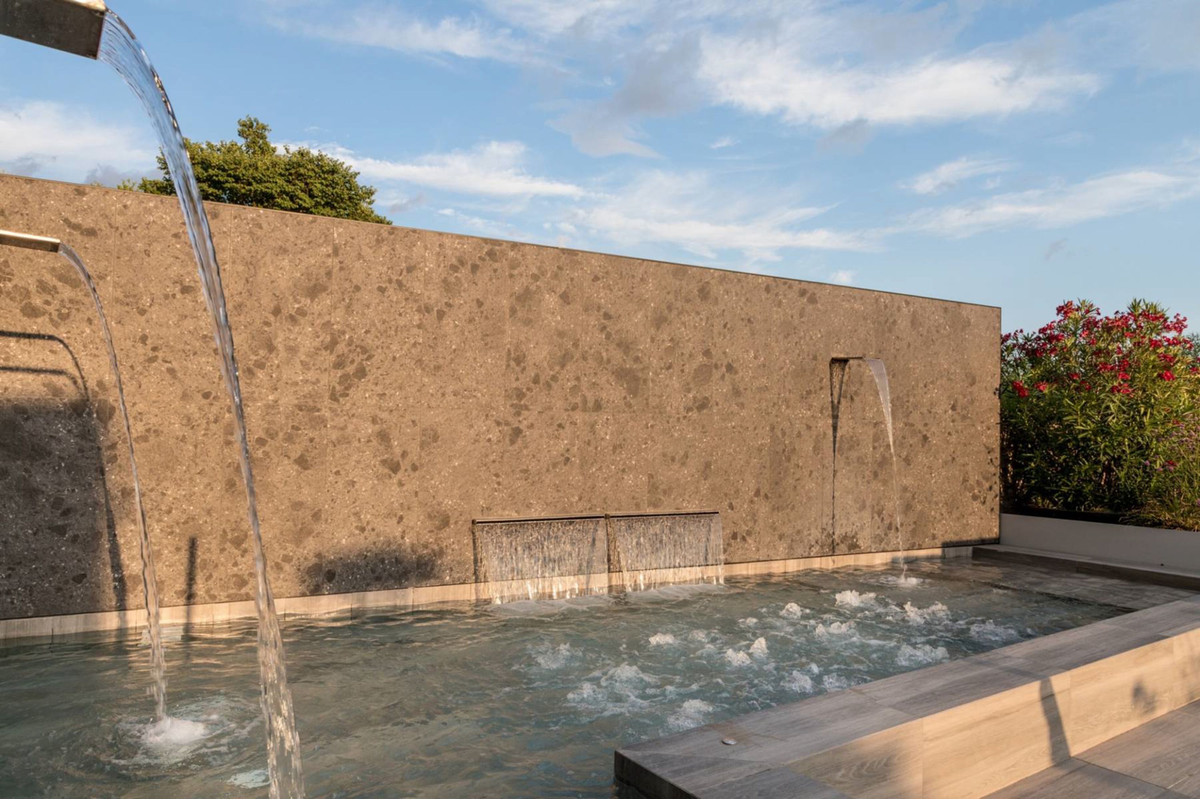 Un área de spa con fuente de agua, pared de piedra y una pequeña piscina.