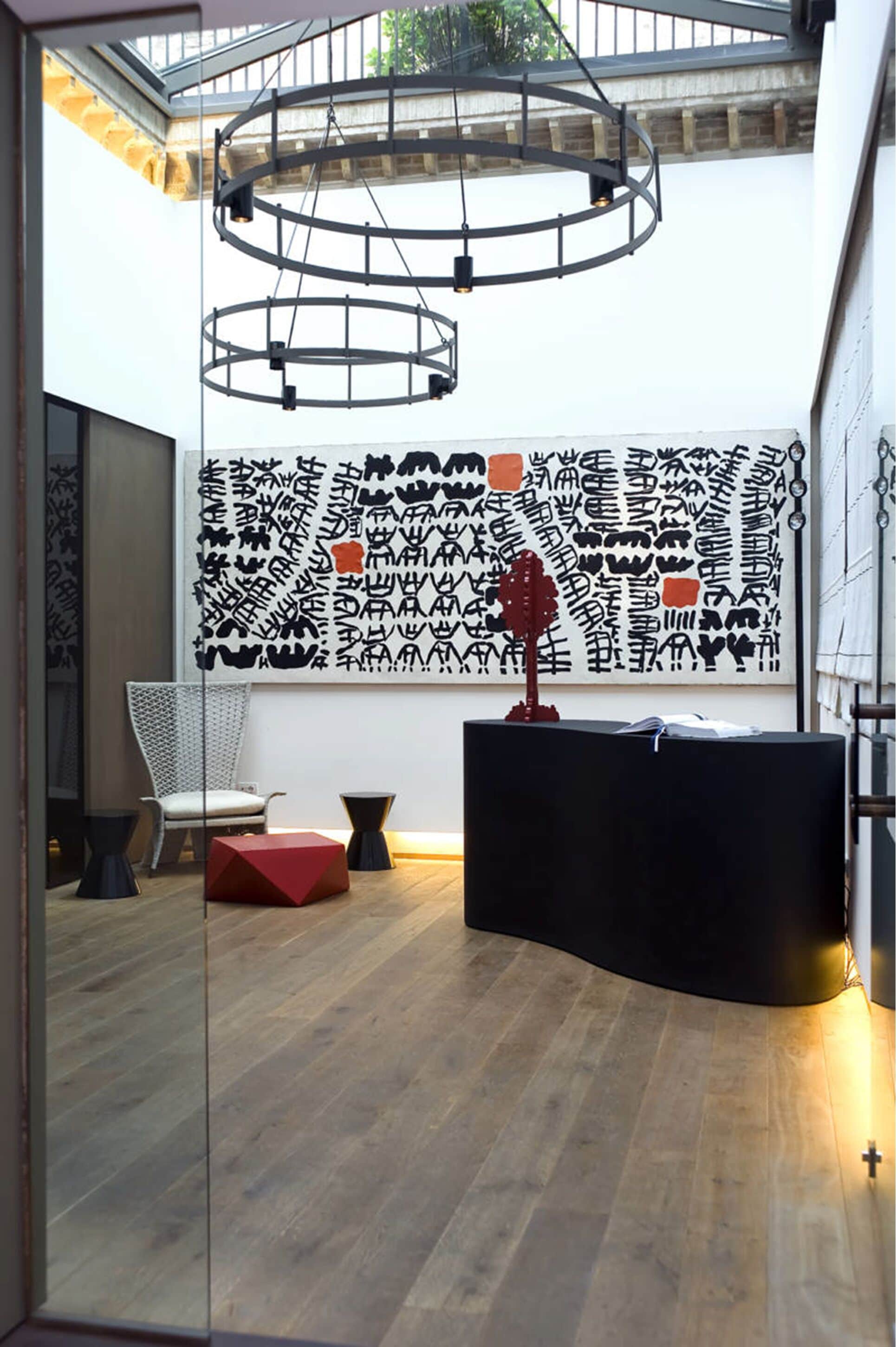 A modern interior with a wooden floor, a black reception desk, a white chair, and a unique black and white patterned wall.