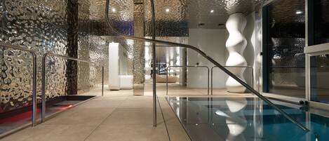 Una piscina interior con barrera de vidrio y techo moderno con textura.