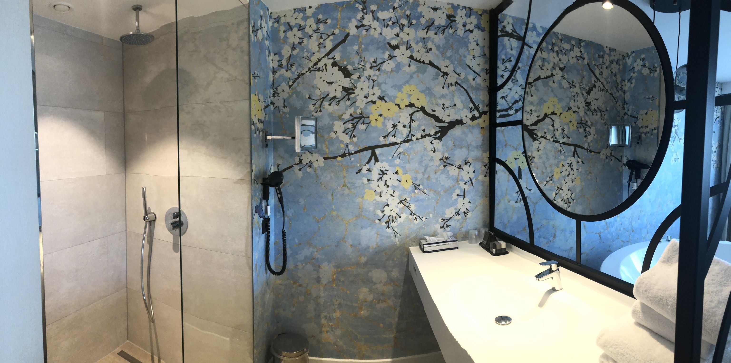 Een badkamer met een douche, wastafel en spiegel.