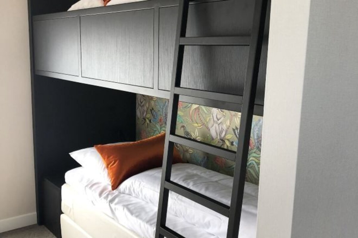 A bunk bed with a headboard and a lower bed, both with white bedding.