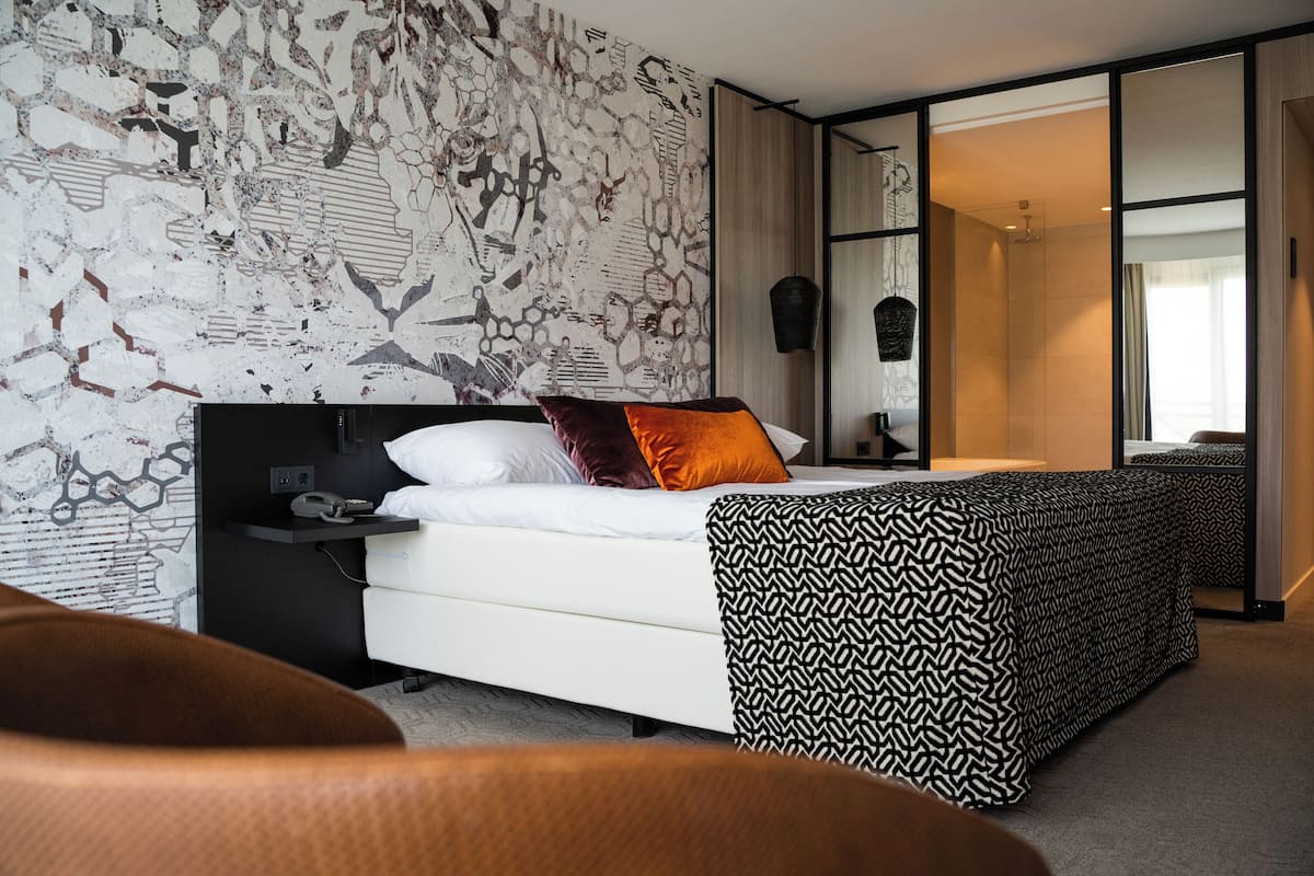 Een moderne hotelkamer met een groot bed, een nachtkastje en een gebreid plaid.