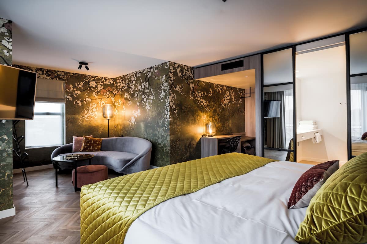 Een moderne hotelkamer met een bed, zithoek en bureau.