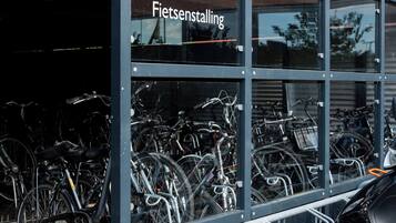 Een fietsverhuurstation met meerdere fietsen en een motorfiets geparkeerd ervoor.