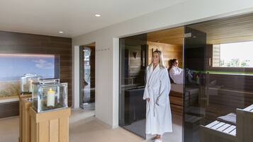 A modern spa room with a glass partition, wooden flooring, and a large window.