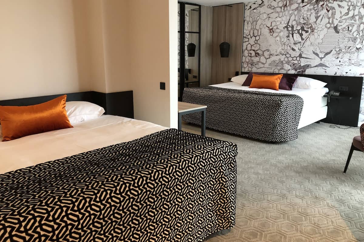Deluxe vierpersoonskamer | Luxe beddengoed, donsdekens, een minibar, een kluis op de kamer