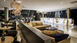Eine moderne Hotelhalle mit Sitzgelegenheiten, Tischen und einer Rezeption.