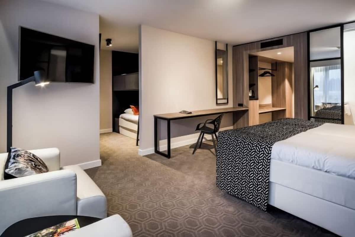 Een hotelkamer met een bed, een bureau, een stoel, een kledingkast en een spiegel.