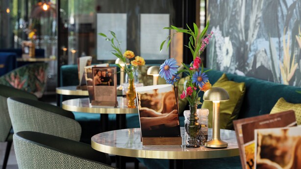 Ein modernes Interieur mit einem grünen Sofa, runden Tischen und floralen Mittelstücken.
