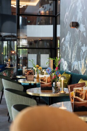 Een modern interieur met een groene bank, ronde tafels en bloemige decoraties.