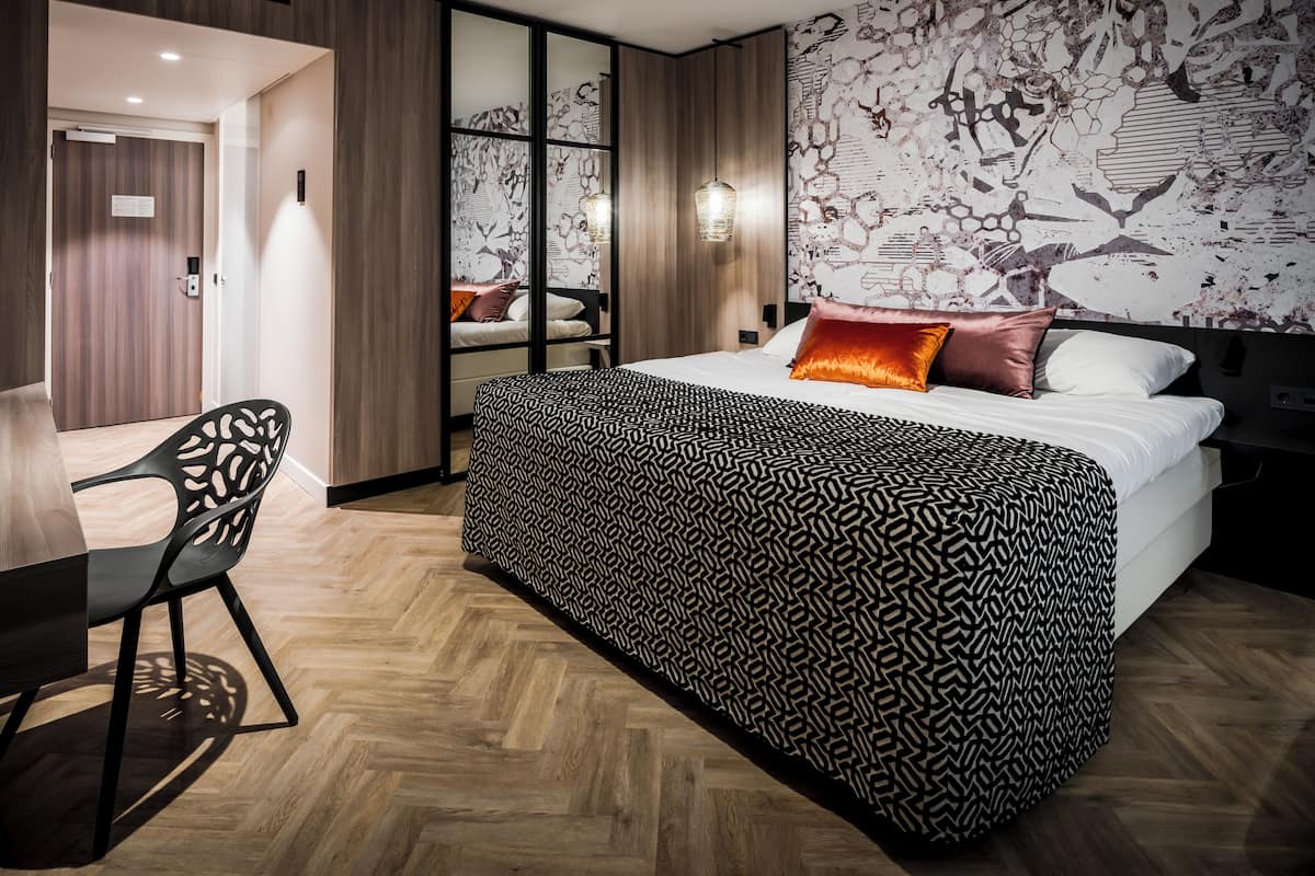 Een moderne hotelkamer met een groot bed, een bureau en een stoel.