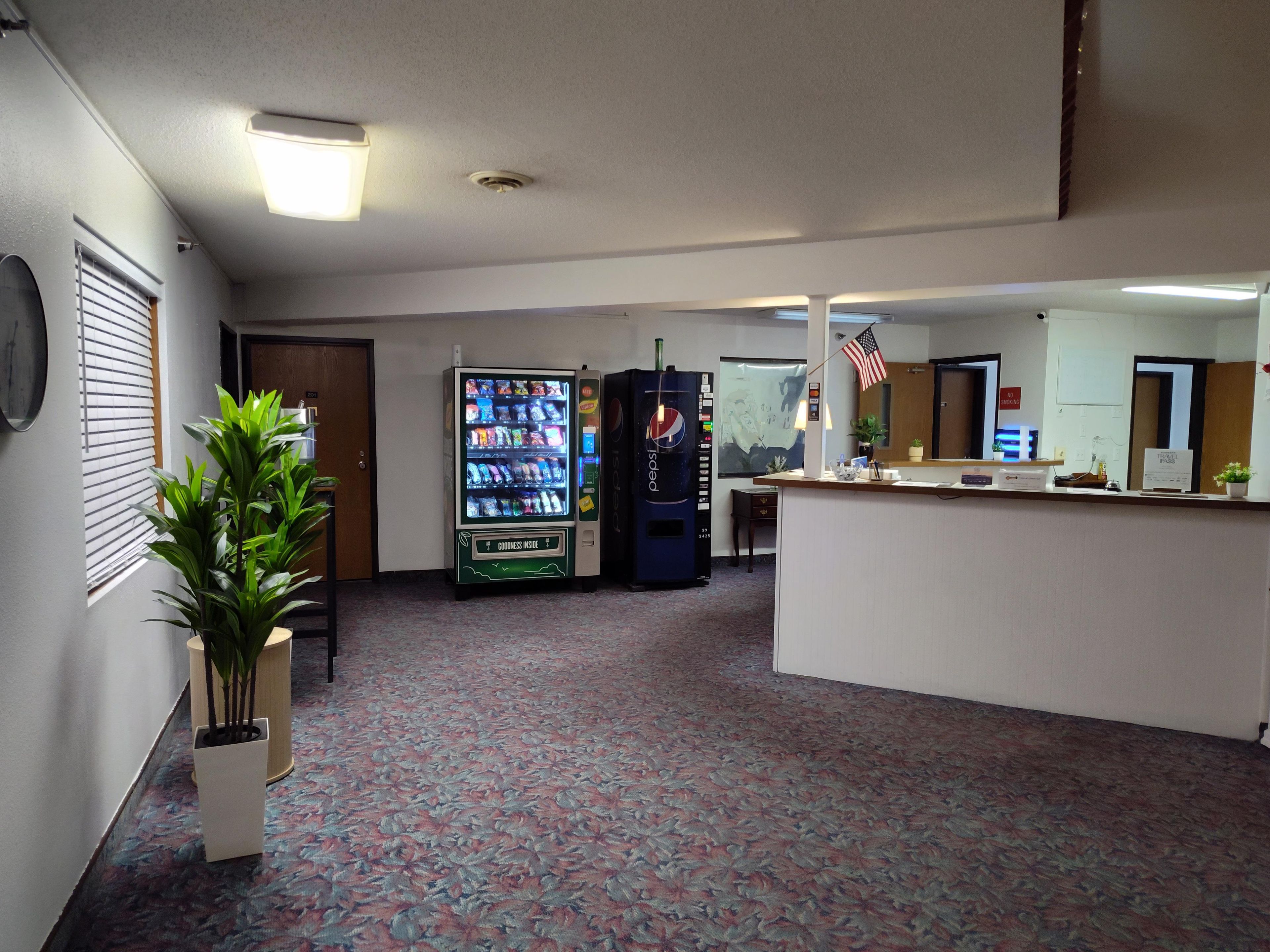 A lobby with a vending machine, a reception desk, and a plant.