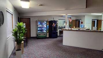 A lobby with a vending machine, a reception desk, and a plant.