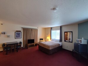 A hotel room with a bed, a desk, a television, a lamp, and a microwave. - Americas Best Value Inn & Suites Clear Lake (Clear Lake)