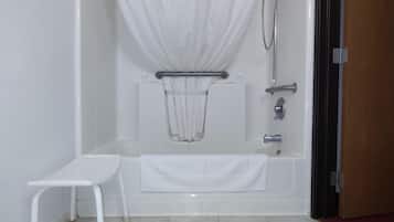 Un baño con bañera, ducha, toallero blanco y un taburete pequeño.