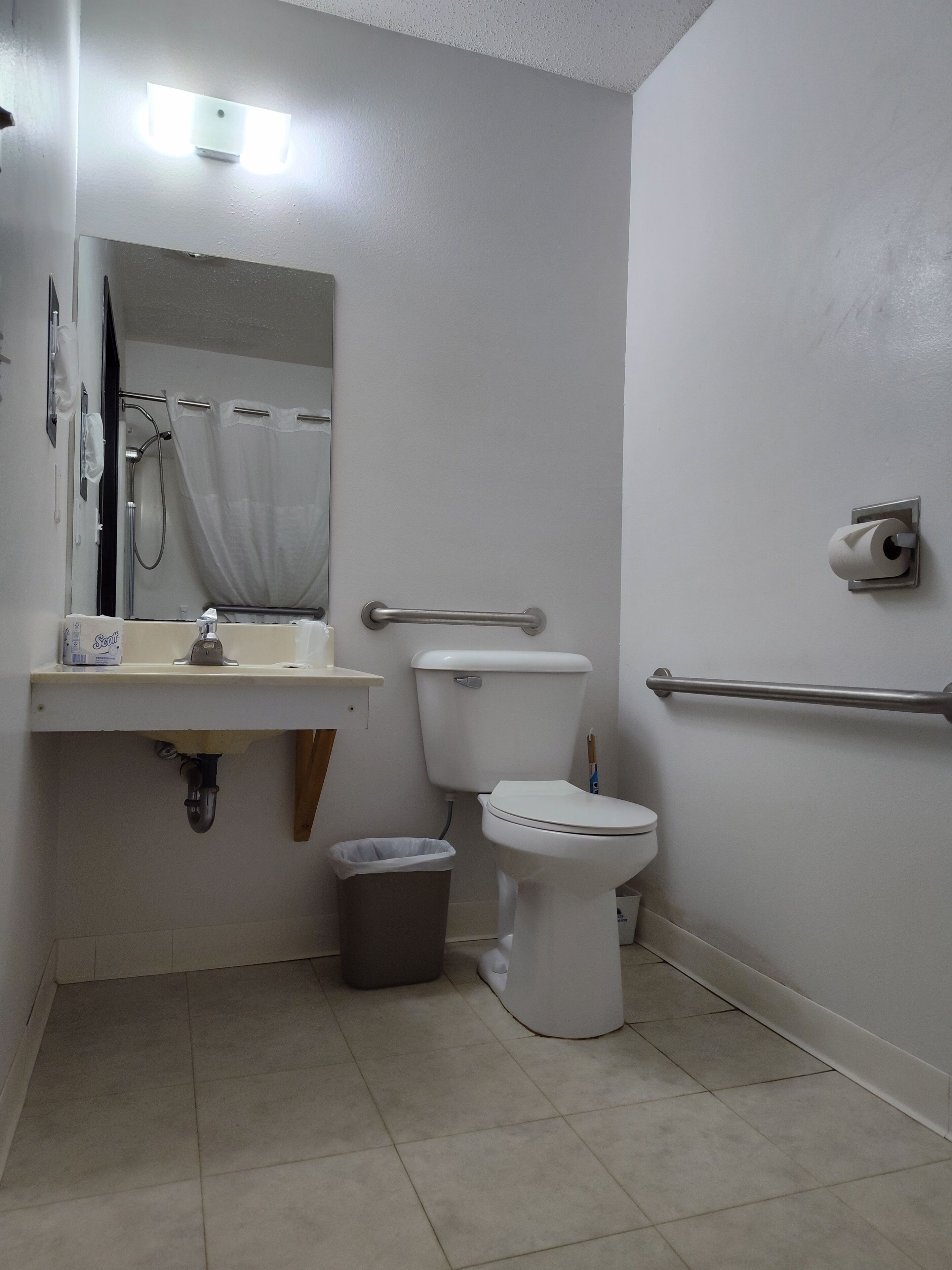 Et badeværelse med toilet, vask og spejl.
