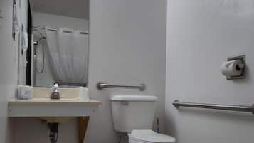 Un baño con inodoro, lavamanos, espejo y barras de apoyo.