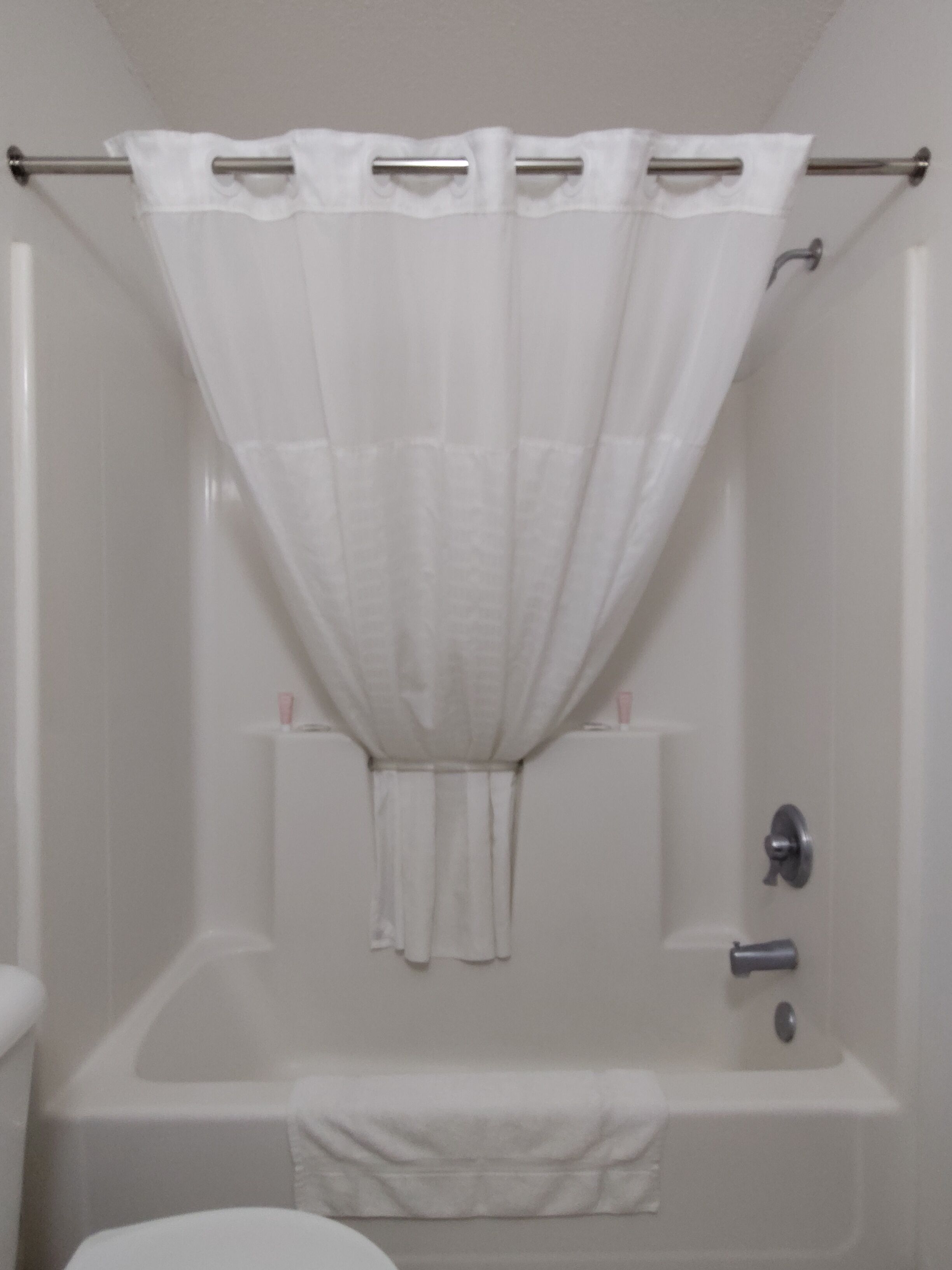 A bathroom with a bathtub, a shower curtain, and a towel rack.