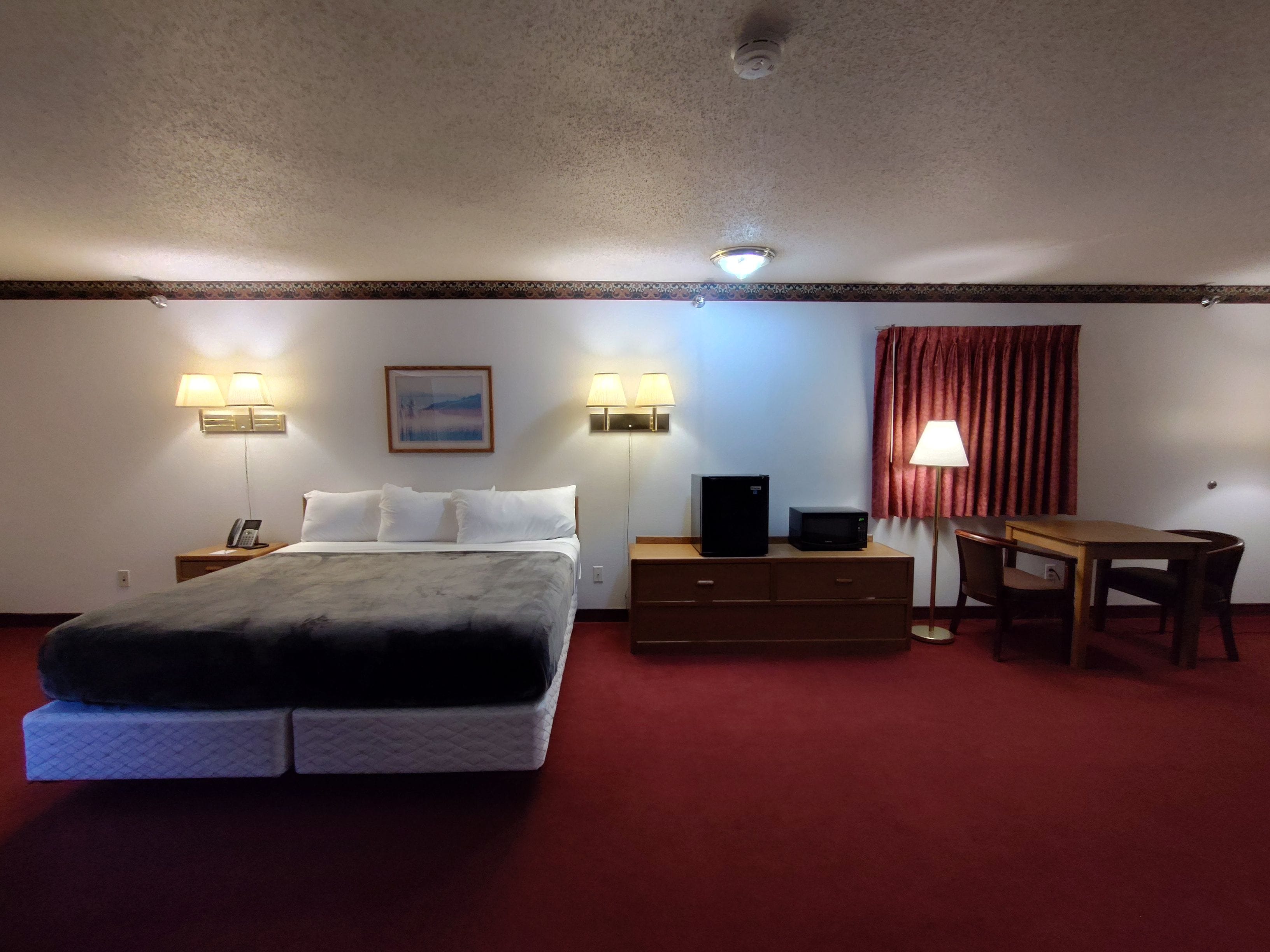 Una habitación de hotel con cama, mesitas de noche, un escritorio y una silla.