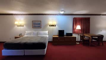 Una habitación de hotel con cama, mesitas de noche, un escritorio y una silla.