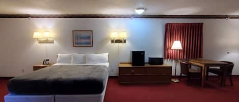 Una habitación de hotel con cama, mesitas de noche, un escritorio y una silla.