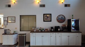A kitchen with a white cabinet, a refrigerator, and a coffee maker.