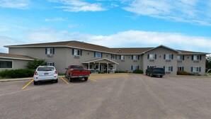 A multi-story hotel with a central entrance, parking lot, and several vehicles parked. - Americas Best Value Inn & Suites Clear Lake (Clear Lake)