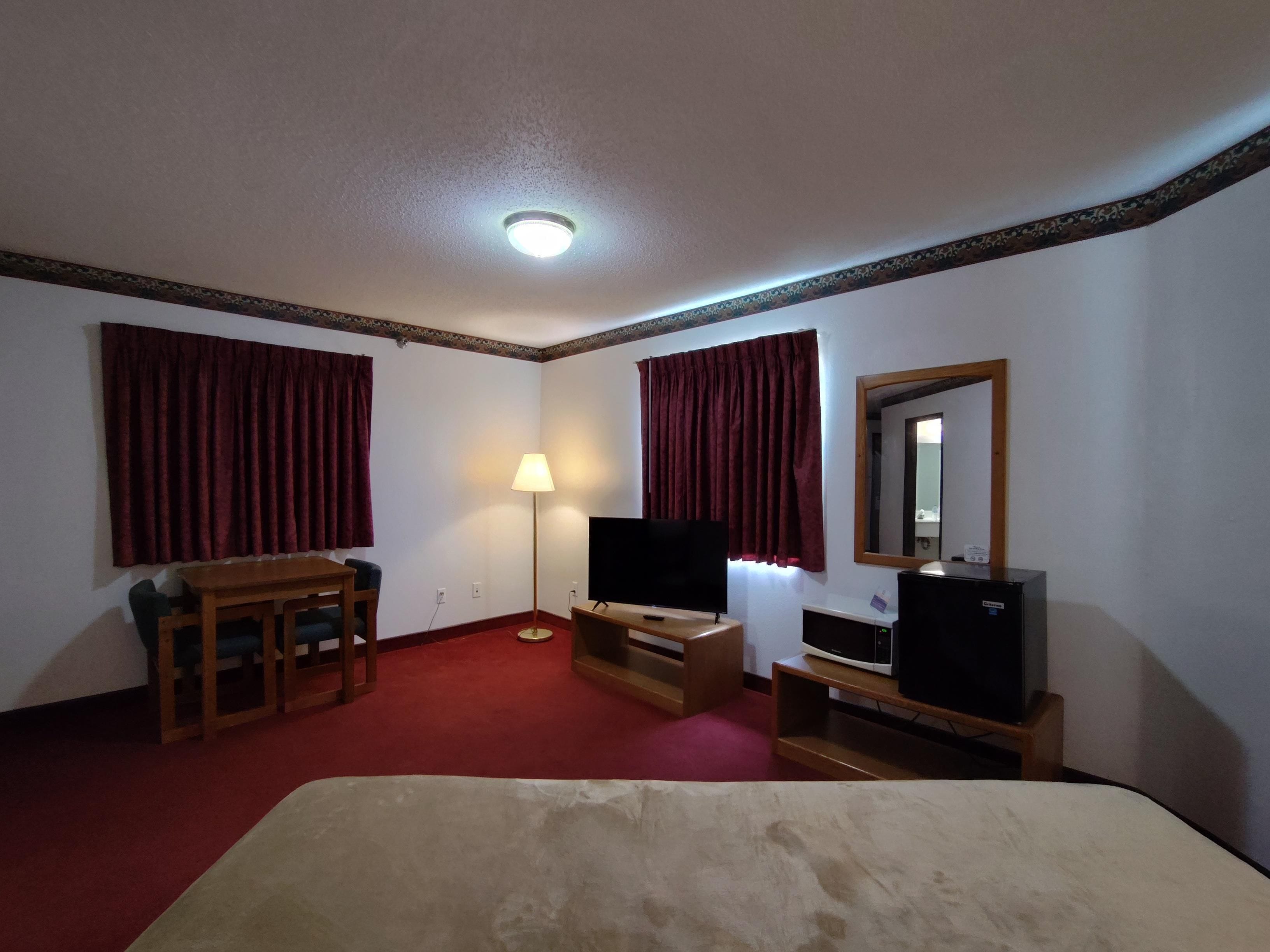 Une chambre d’hôtel équipée d’un lit, d’un bureau, d’une chaise, d’une télévision, d’une lampe et d’un miroir.