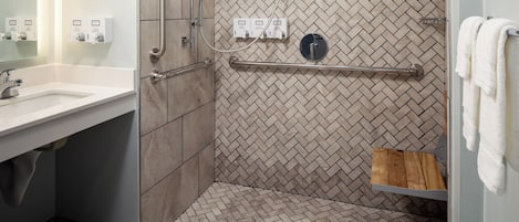 A modern bathroom with a shower, a vanity with a sink, and a towel rack.