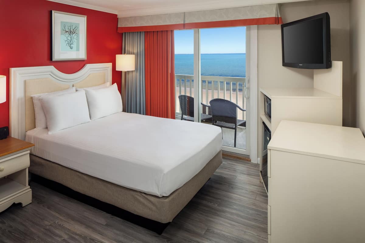Habitación de hotel con una cama grande, televisión, escritorio y vistas al océano.