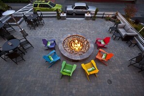 An outdoor seating area with a central fire pit surrounded by colorful chairs and tables. - Surfside Hotel and Suites (Provincetown)