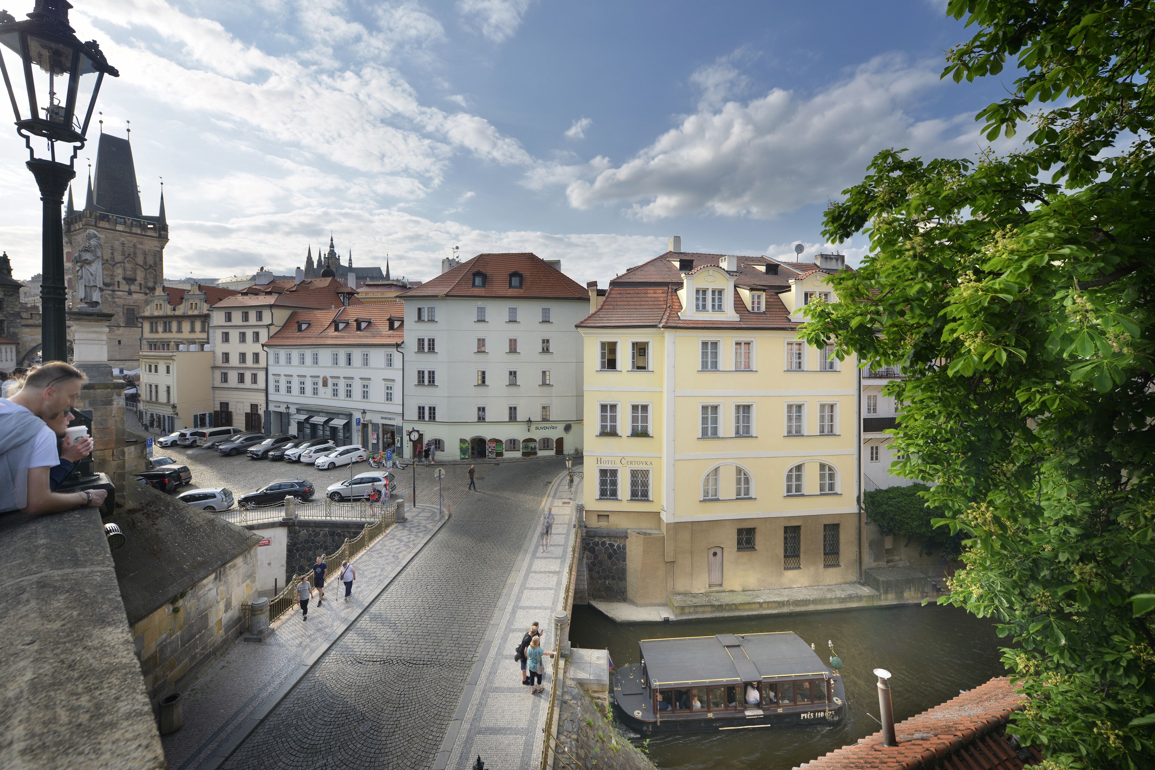 A historic street with cobblestone pavement, a canal, and traditional buildings including a hotel.