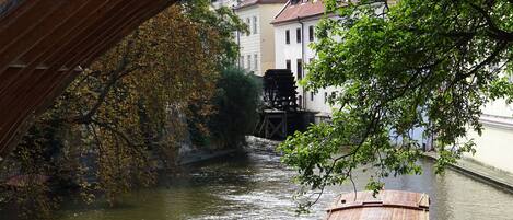 A wooden boat named 'Praha' on a river under a bridge.