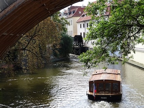 A wooden boat named 'Praha' on a river under a bridge. - Hotel Čertovka (Prague)