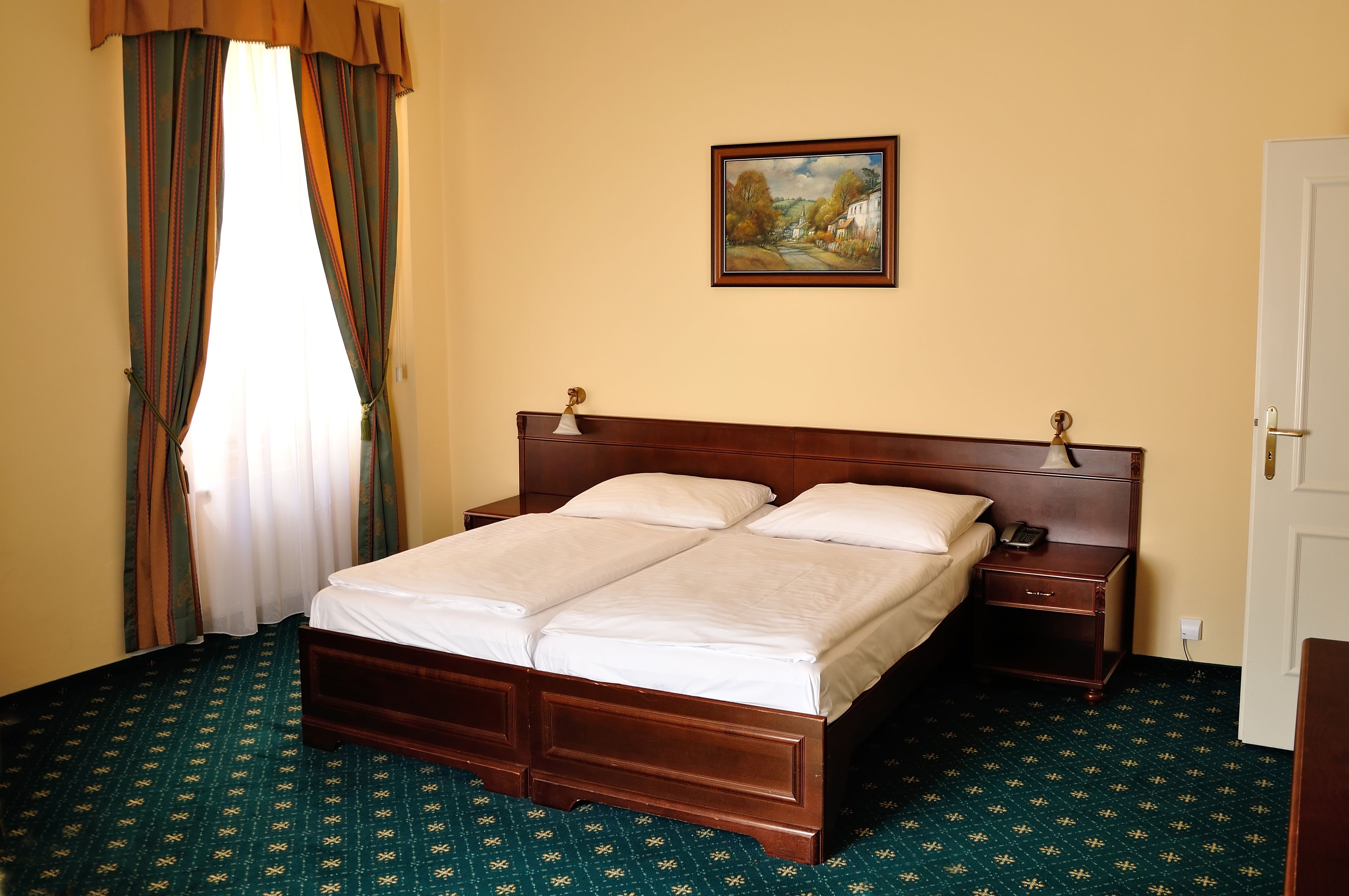 Uma cama de casal bem arrumada com cabeceira de madeira, mesa de cabeceira com luminária e um quadro na parede.