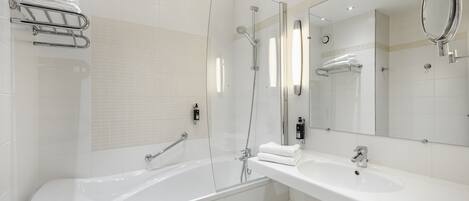 Un baño moderno con ducha de vidrio, bañera independiente y tocador con espejo.