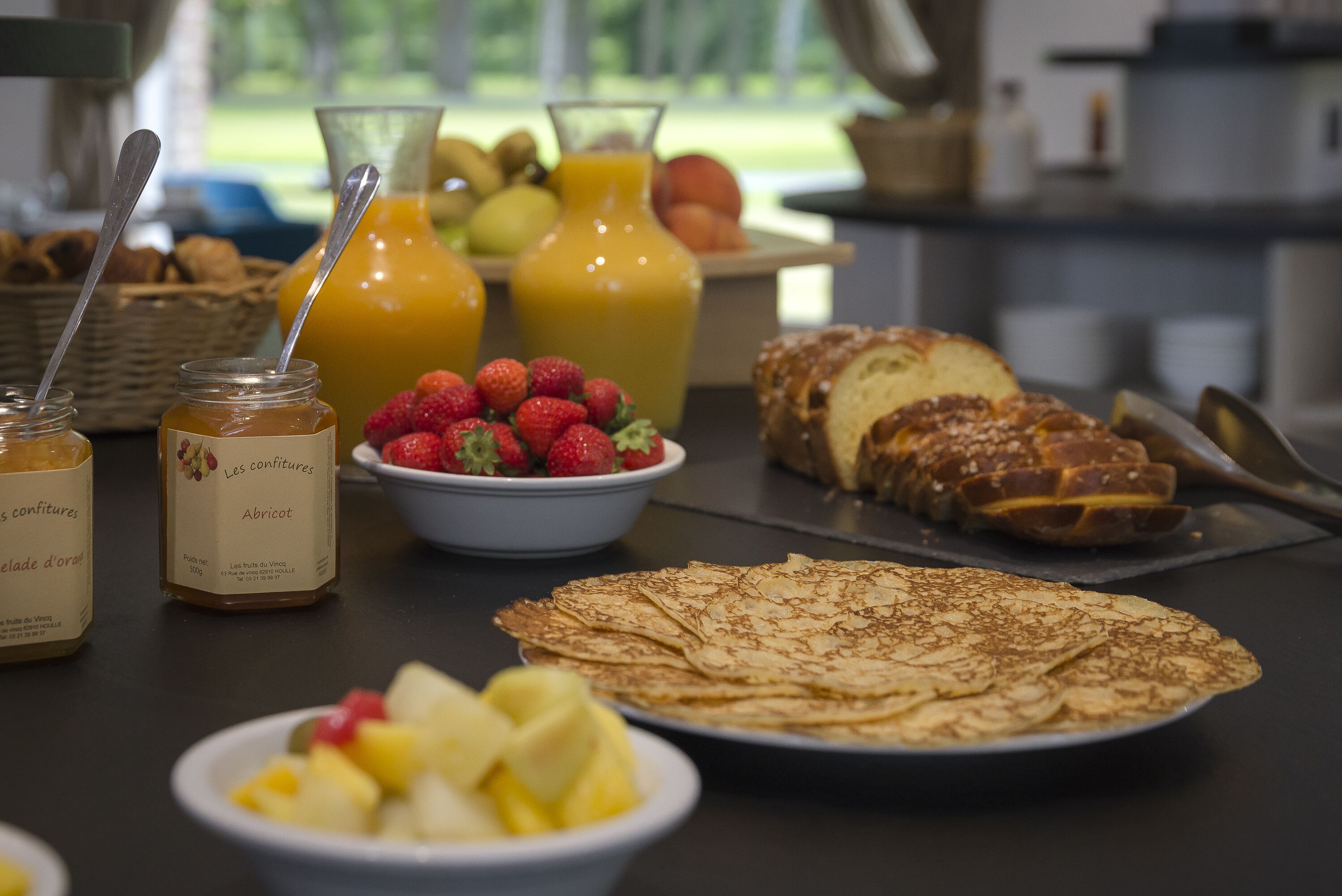 A breakfast buffet with various food items including crepes, fruits, and beverages.